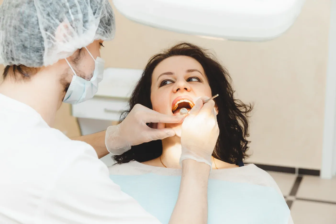 positive-darkhaired-woman-sits-dentist-s-office-checkup-dentist-examining-woman-s-teeth (1).webp